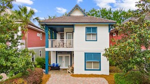 A two-story house with a balcony, a garage, and a driveway.