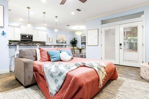 A bedroom with a bed, a chair, a desk, and a dining area.