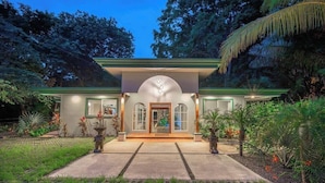 Une maison moderne à la façade symétrique, dotée de grandes fenêtres et d’une entrée centrale.