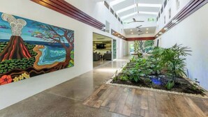 Un vaste espace intérieur doté d’un haut plafond, d’une fresque sur le mur de gauche et d’un petit jardin intérieur sur la droite.