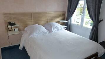 A neatly made bed with white linens in a hotel room.