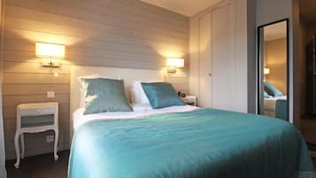 A bedroom with a bed, two bedside tables, and wall-mounted lamps.