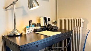 A hotel desk with a desk lamp, a kettle, a telephone, a notepad, and a cup. - Logis Hotel le Faisan Dore (Écouché-les-Vallées)