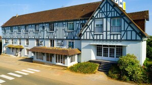 Un edificio de estilo Tudor tradicional con un letrero de pub, un pequeño espacio de asientos al aire libre y una escalera que conduce a la entrada.