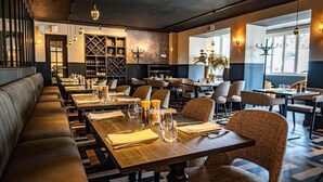 Un restaurante con mesas comunitarias largas, asientos acolchados y un diseño de interiores moderno.