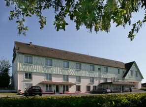 Un grand bâtiment à deux étages, de style architectural traditionnel, caractérisé par un toit à pignon bien visible et une façade symétrique.