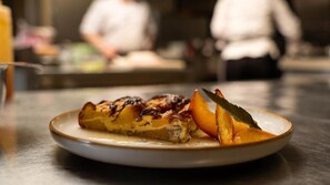 Un plato con un guiso a la parrilla y fruta cortada sobre una mesa en un restaurante.
