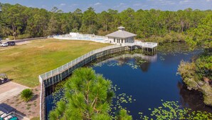 A lakeside lodge with a dock extending into the water, surrounded by dense forest. - Seagrove Highlands By Panhandle Getaways (Santa Rosa Beach)