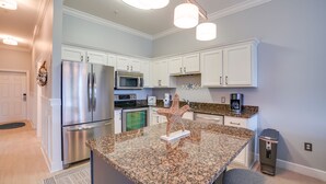 A modern kitchen with white cabinetry, stainless steel appliances, granite countertops, and pendant lighting. - Seagrove Highlands By Panhandle Getaways (Santa Rosa Beach)