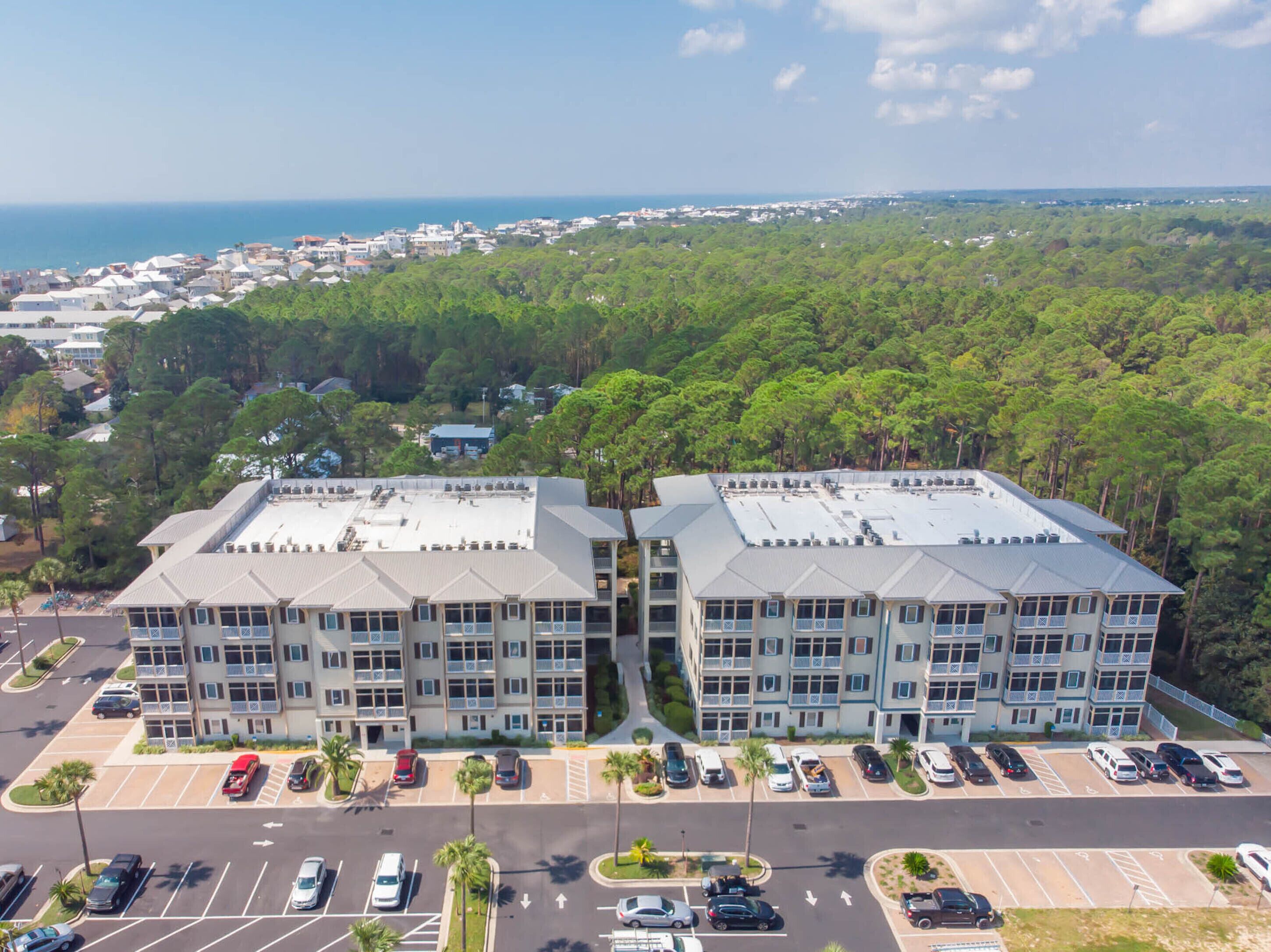 A multi-story hotel with a parking lot and a view of the ocean.