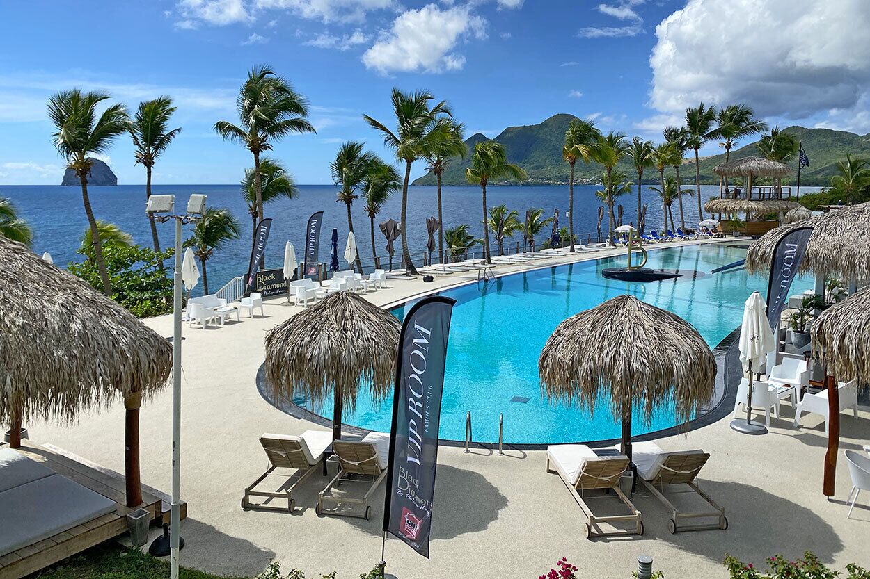 A pool area with lounge chairs, thatched umbrellas, and flags indicating a VIP room.