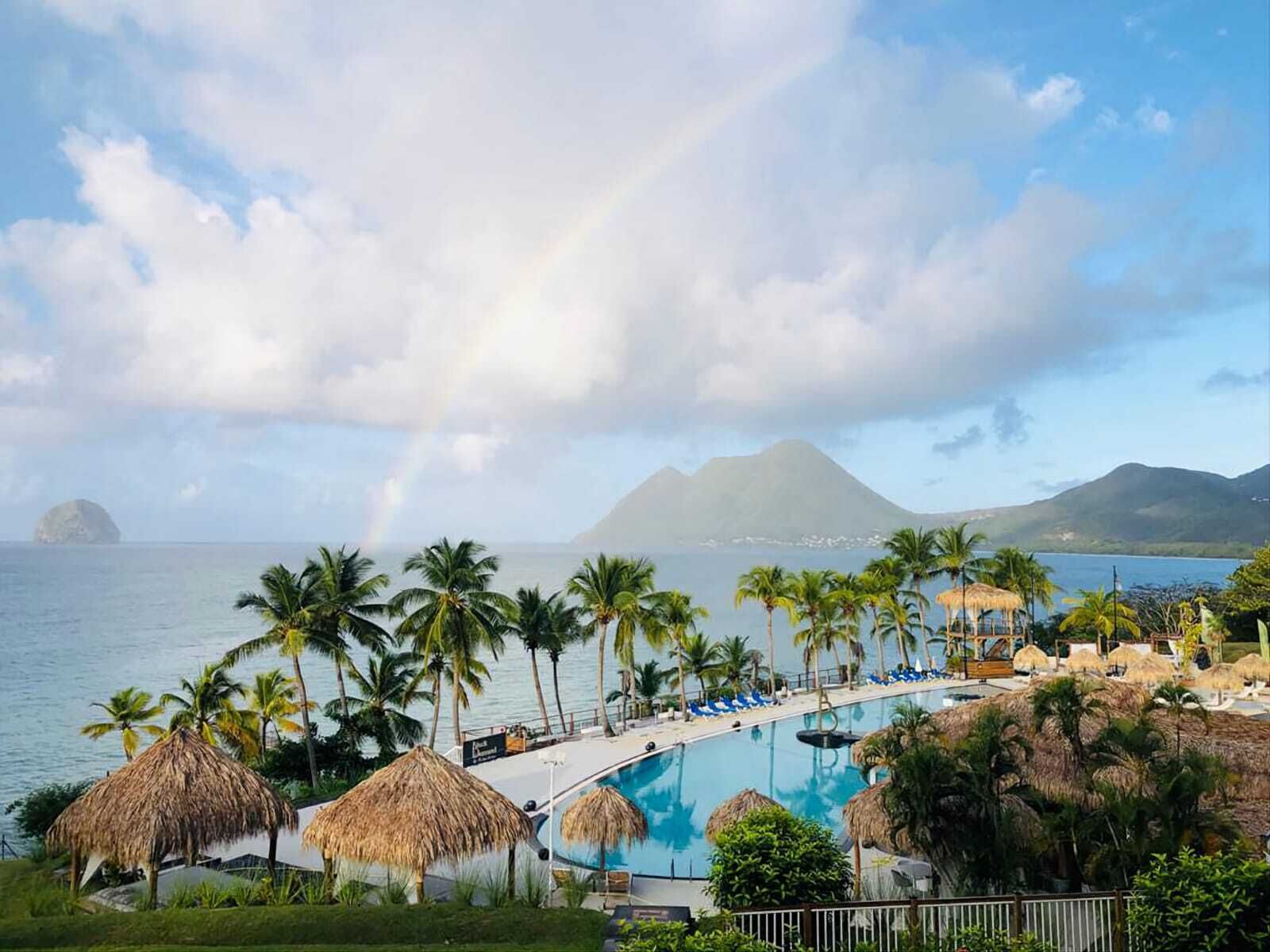 Ein Resort mit Pool, Palmen und Blick auf Ozean und Berge.