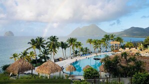Ein Resort mit Pool, Palmen und Blick auf Ozean und Berge.