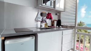 Eine moderne Küche mit weißen Schränken, einer eingebauten Mikrowelle und einem kleinen Kühlschrank.