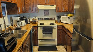 A modern kitchen with wooden cabinets, stainless steel appliances, and a black countertop.