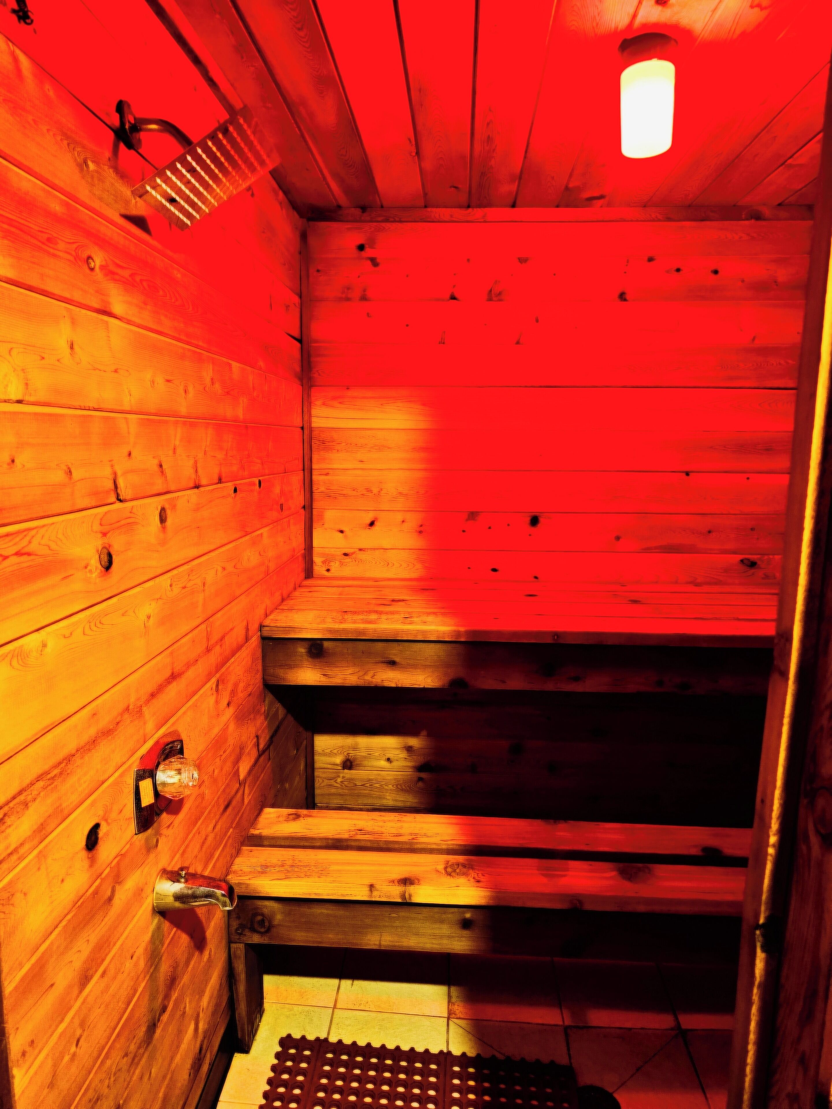 A wooden sauna with a sloped ceiling and a small window.