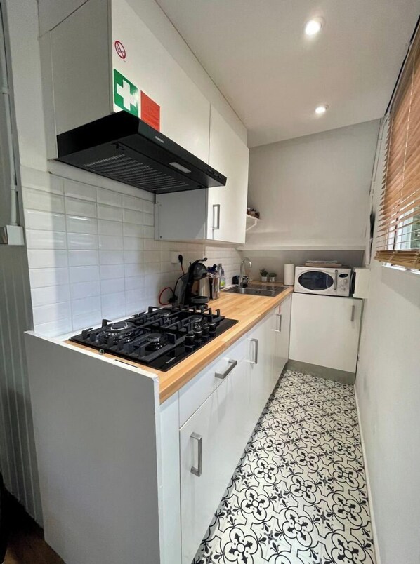 A compact kitchen with white cabinets, a black stove, and a patterned floor.