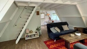 A loft-style living space with a staircase, a sofa, a coffee table, and a red patterned rug.