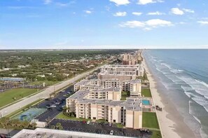 A coastal residential area with multi-story buildings, a beach, and a parking lot.
