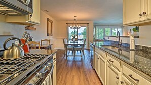 A kitchen with a gas stove, a dining table with chairs, and a view of the outdoors through a window. - Vernon Condo w/ Deck, Near Appalachian Trail! (Vernon Township)
