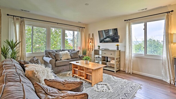 A living room with a sofa, coffee table, and TV. There are windows with curtains, a plant, and a lamp. - Vernon Condo w/ Deck, Near Appalachian Trail! (Vernon Township)