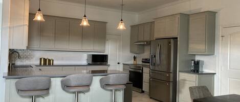 A modern kitchen with a central island, stainless steel appliances, and pendant lighting.