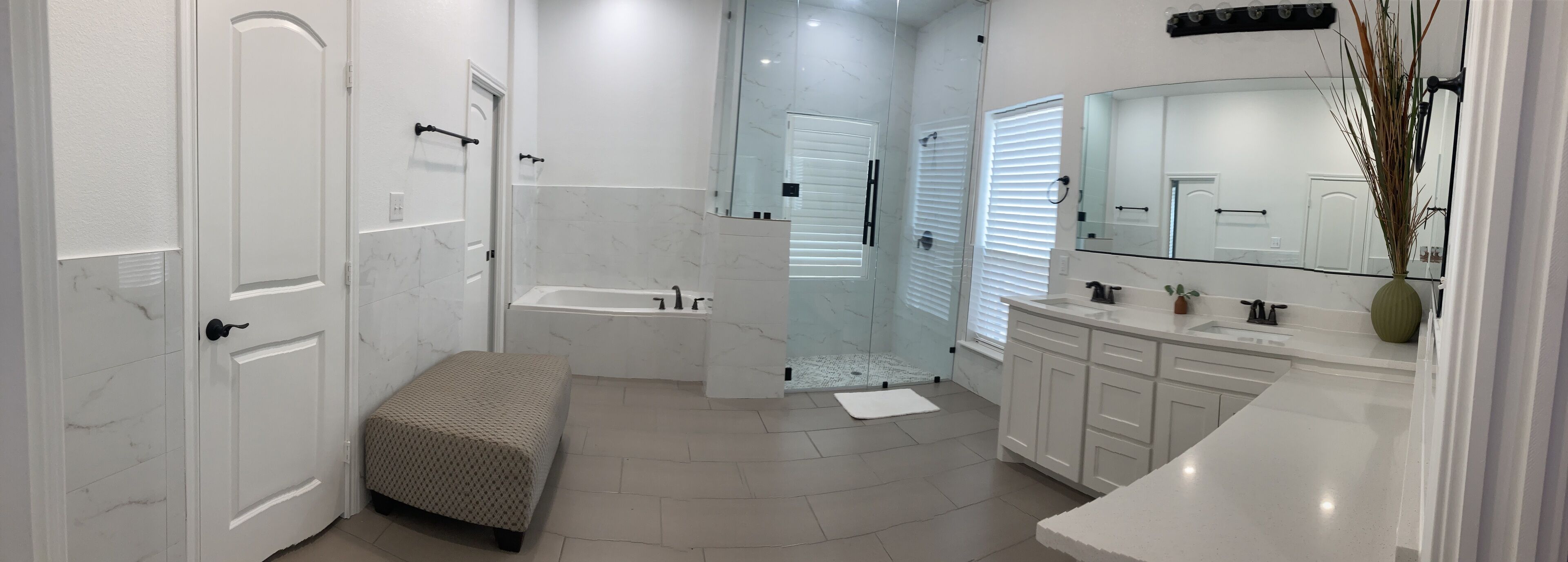Un baño moderno con bañera, ducha y un espejo grande.
