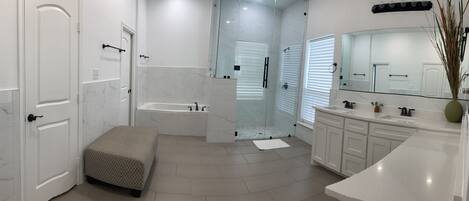Un baño moderno con bañera, ducha y un espejo grande.