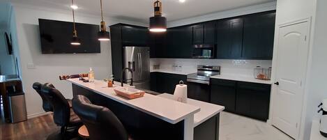 A modern kitchen with dark cabinets, stainless steel appliances, and a central island with bar stools.