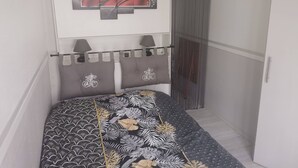 Ein kleiner, kompakter Raum mit einem Bett, einem an der Wand befestigten Fernseher und einem Vorhang.