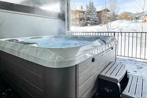 A hot tub with a view of a snowy landscape and buildings.