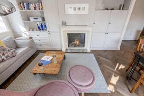 Una sala de estar con chimenea, un sofá, una mesa de centro y una estantería.