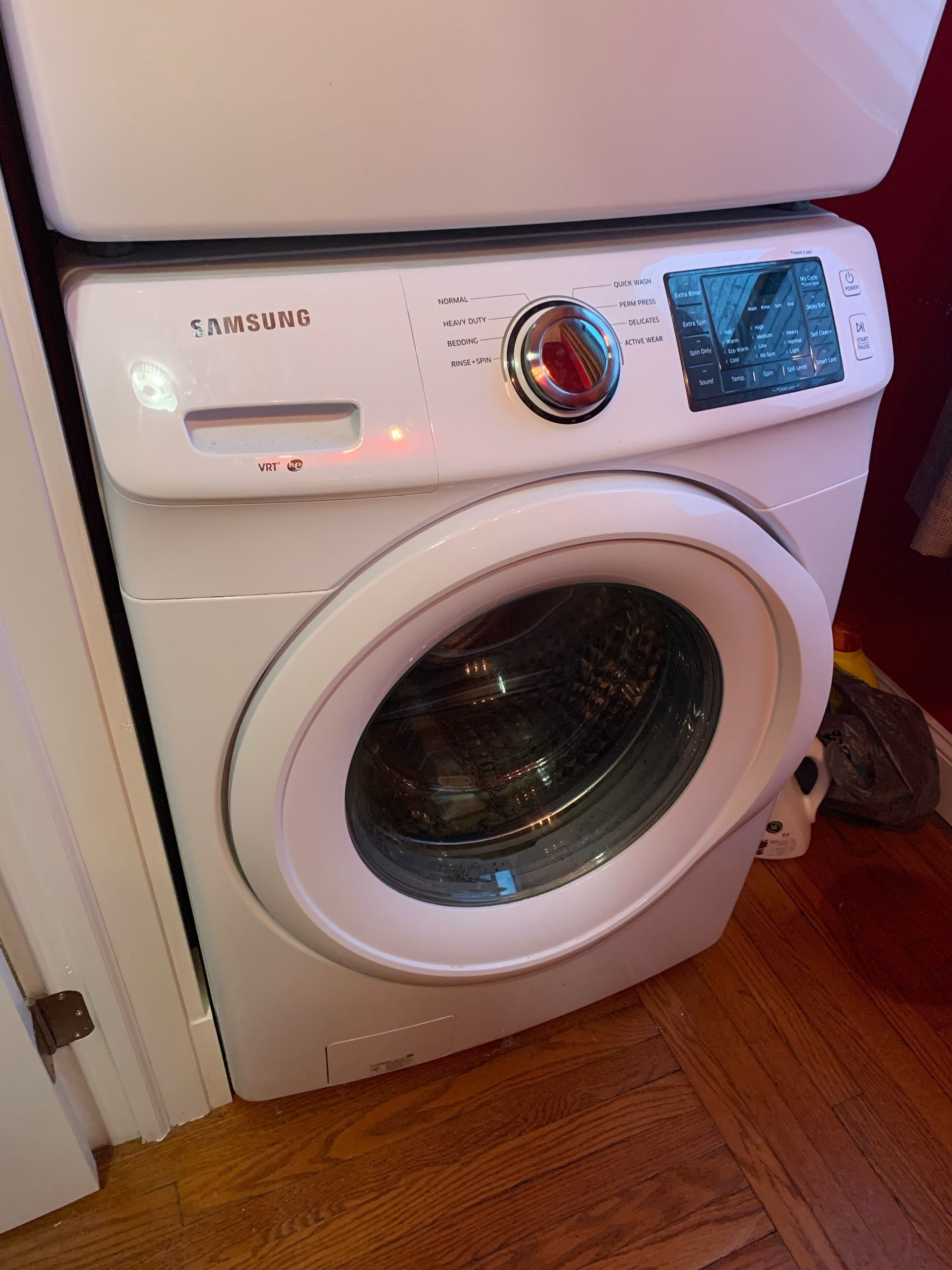 Máquina de lavar roupa Samsung com painel de controlo digital, porta frontal e comandos para diversas opções de lavagem.