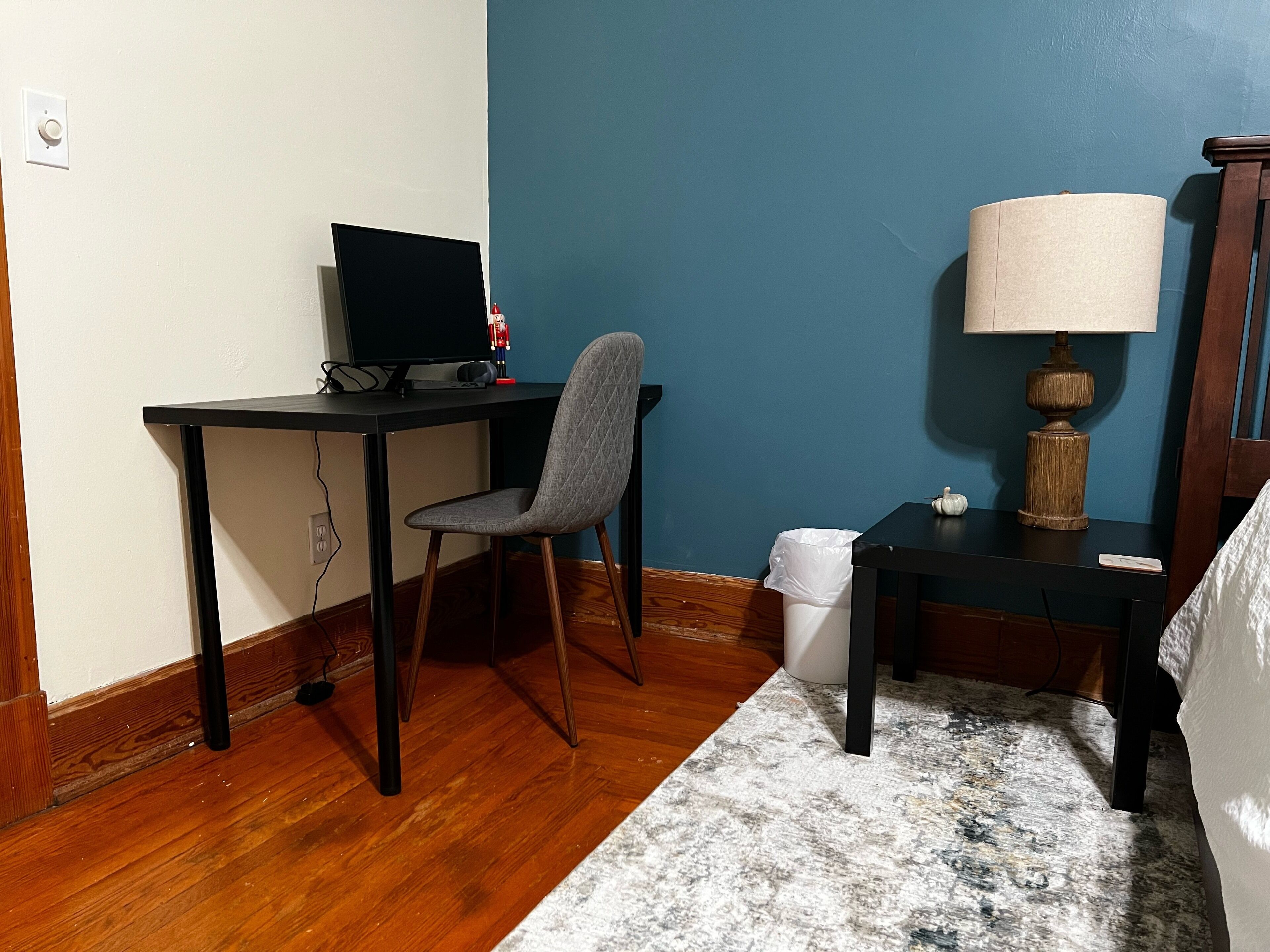 Une petite pièce avec un bureau, une chaise et une lampe.