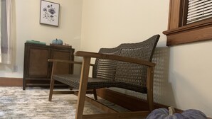 Ein hölzerner Stuhl mit einem gewobenen Rücken und Kissen, ein kleiner Tisch mit grüner Decke und einem Kürbis, und ein großer Kürbis auf einem Marmorboden.