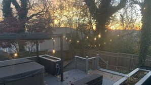 Eine Terrasse mit Whirlpool, überdachter Sitzgelegenheit und Holzlattenzaun.