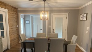 A dining area with a wooden table, six chairs, and a pendant light. - Newly Renovated Ranch House with  Open Concept (Fredericksburg)
