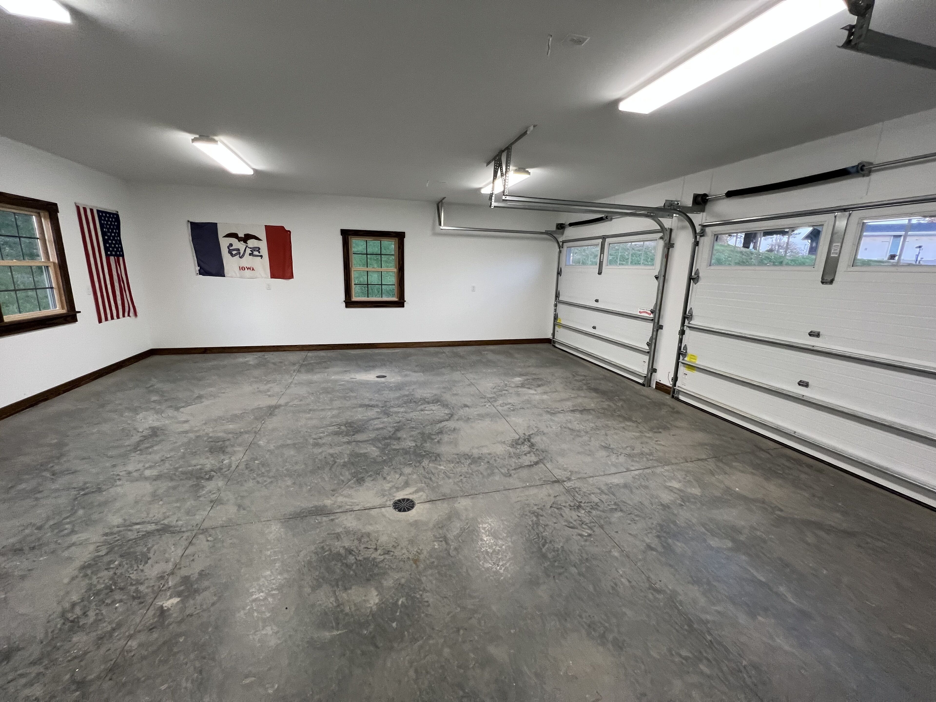 A spacious garage with a concrete floor, a large garage door, and an American flag.