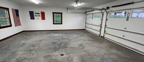 A spacious garage with a concrete floor, a large garage door, and an American flag.