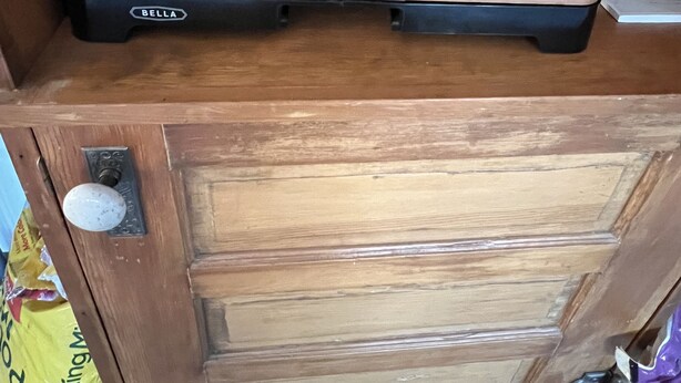 A wooden cabinet with a flat surface on top, a drawer below, and a bag of Potting Mix to the left.