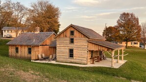 A log cabin with a stone foundation, a covered porch, and a small patio area with outdoor seating.