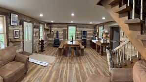 A rustic interior with a wooden staircase, a dining area, and a sofa.