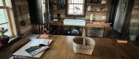 Una cucina rustica con pareti in legno, un tavolo di legno, un televisore e diversi oggetti da cucina.