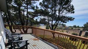 Eine Holzterrasse mit zwei Adirondack-Stühlen und einem Holgitter.