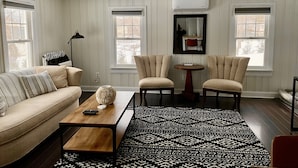 A living room with a sofa, two armchairs, a coffee table, a patterned rug, and a ceiling fan. - Cozy SK Cottage 💜 (South Kingstown)