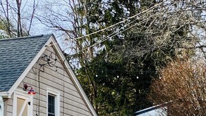 A two-story house with a stone wall in front, a garage, and a shed. - Cozy SK Cottage 💜 (South Kingstown)