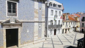 A courtyard with a tiled building featuring a large open doorway and a balcony.