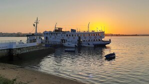 A large ferry docked at a pier with a restaurant bar named "RESTAURANTE BAR" and "LISBOA VISTA" on its side. - Legendary Bay - Themed Suite (Seixal)