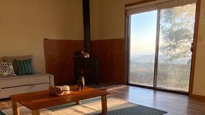 A living room with a sofa, a wooden coffee table, a fireplace, and a view through a large sliding glass door. - Enchanting View, Sequoia/Kings Canyon PKs Getaway (Miramonte)