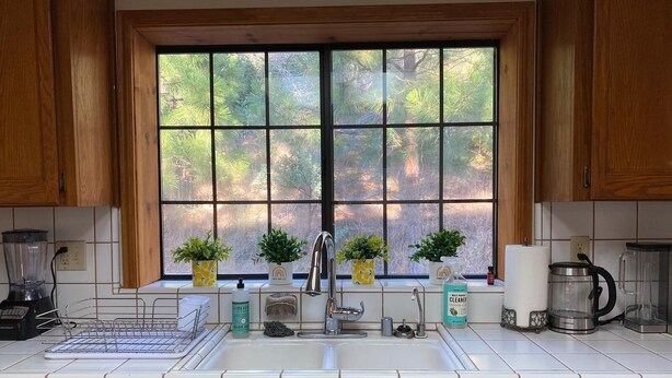 A kitchen with a large window, wooden cabinets, a sink, a dishwasher, and various kitchen appliances. - Enchanting View, Sequoia/Kings Canyon PKs Getaway (Miramonte)